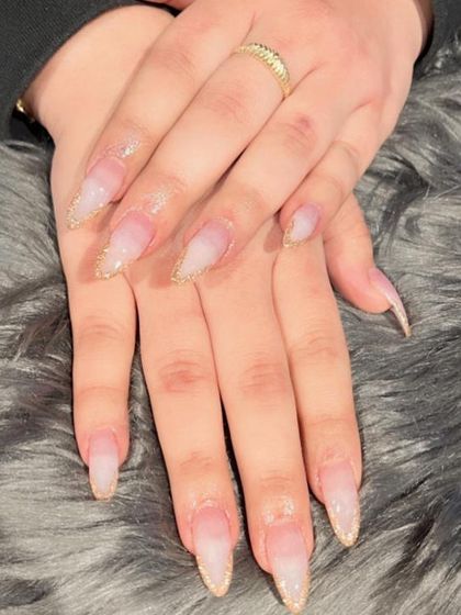 A subtle yet glamorous look with long, stiletto-shaped nails and delicate gold glitter tips.