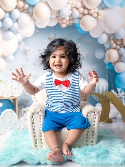 Pure happiness captured in a frame. This little boy's joyful expression and waving hands make for a perfect first birthday memory.