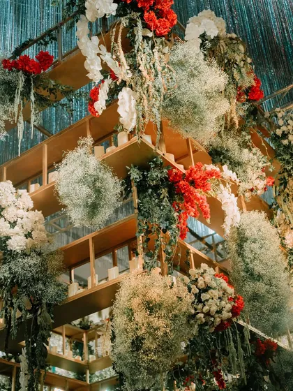 A maximalist floral installation from the "Velvet & Moody Luxe" theme, featuring a wooden grid structure overflowing with white and red flowers, baby's breath, and greenery.