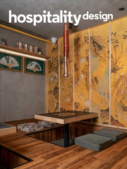 A closer view of the sunken dining nook at Seoul. The design combines warm wood flooring, concrete-finish walls, and curated cultural artifacts like framed fans to create a space that feels both modern and deeply rooted in heritage.