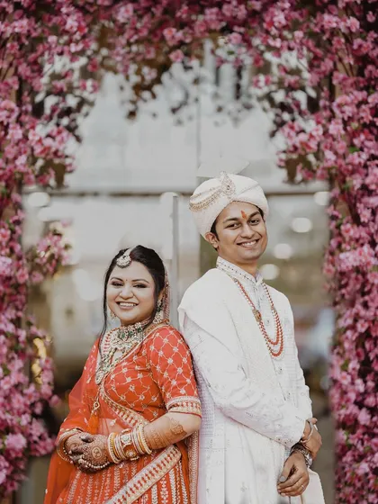 A lovely back-to-back portrait of the bride and groom against a stunning floral archway. Their happy smiles show the excitement of starting their new life together.