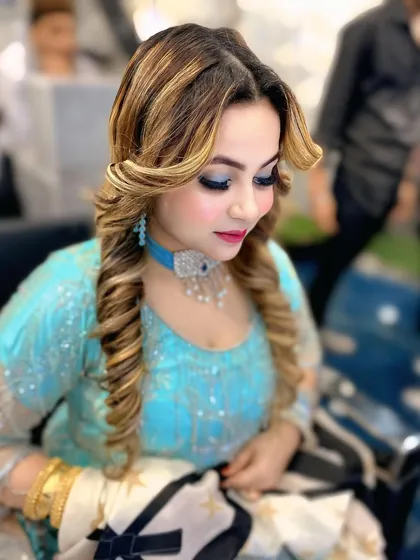 A soft, romantic hairstyle with face framing curls and highlights. This look is paired with glamorous eye makeup, making it ideal for an evening event or sangeet.