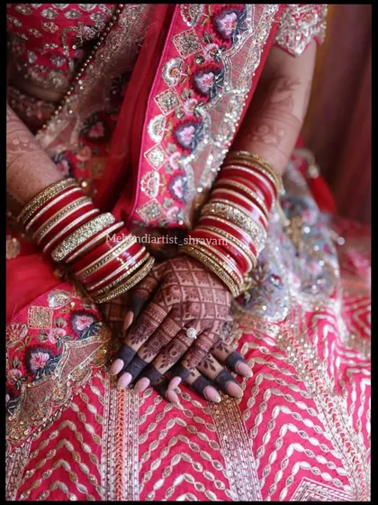 The final stain is everything. This photo shows the rich, dark color achieved with my 100% natural henna paste, beautifully complementing the bride's traditional red and white bangles.