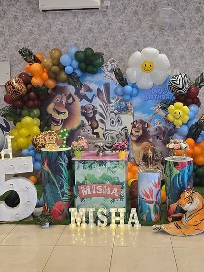 A full view of the lively Madagascar themed 5th birthday party, showcasing all the characters, props, and a large marquee number '5'.