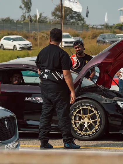 A group of racers and crew members gather around a stunning purple Audi R8 with gold wheels, a perfect example of the high-end car culture at our events.