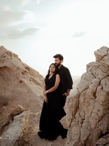 An intimate portrait set against the rugged rock formations of Dubai. The dramatic landscape and the couple's serene pose create a powerful and artistic elopement photograph.