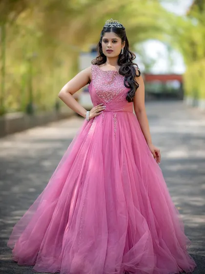 A full-length shot of a model in a beautiful pink ball gown, looking like a modern-day princess.