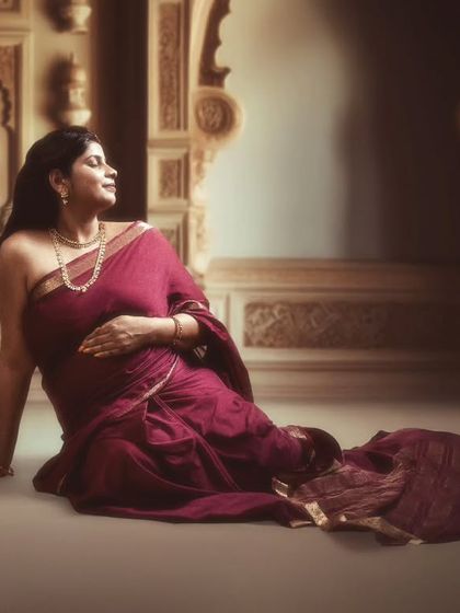 A tale of grace, elegance, and the journey of motherhood, captured amidst whispers of heritage-inspired architecture in a deep maroon saree.