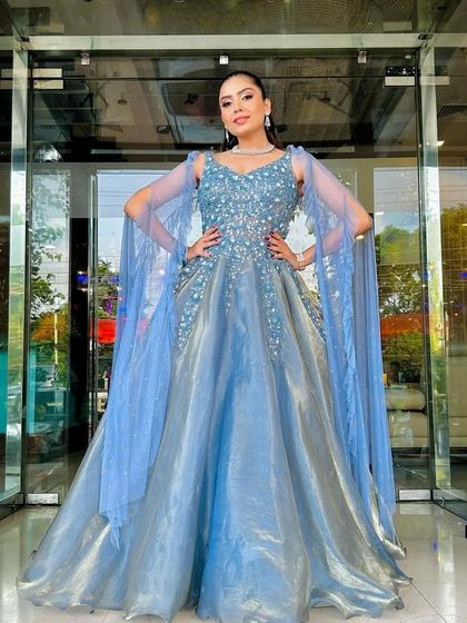 A full front view of the shimmering blue-grey gown with its elegant cape sleeves, a perfect rental for a reception or formal party.