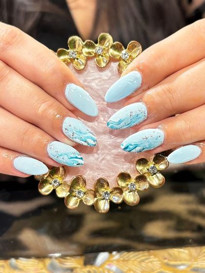 A soft and dreamy light blue marble effect with delicate teal veining and specks of gold foil.