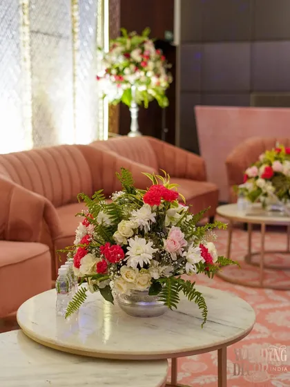 A comfortable lounge area with plush pink sofas and marble-topped coffee tables. A simple yet elegant floral arrangement adds a touch of freshness to the space.