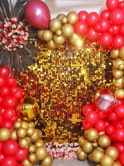 A glamorous balloon decoration featuring a gold sequin wall framed by an arch of red and gold balloons, perfect for birthdays, anniversaries, or parties.
