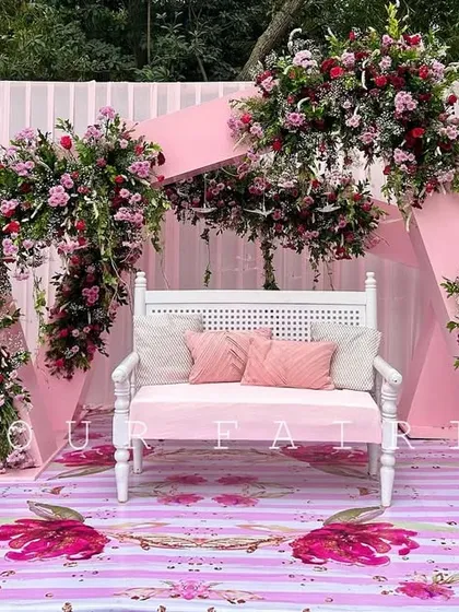 We designed this enchanting outdoor ceremony with a modern pastel pink theme. The setup features a custom printed floral floor, geometric arches, and lush flower arrangements, creating a fairytale setting.
