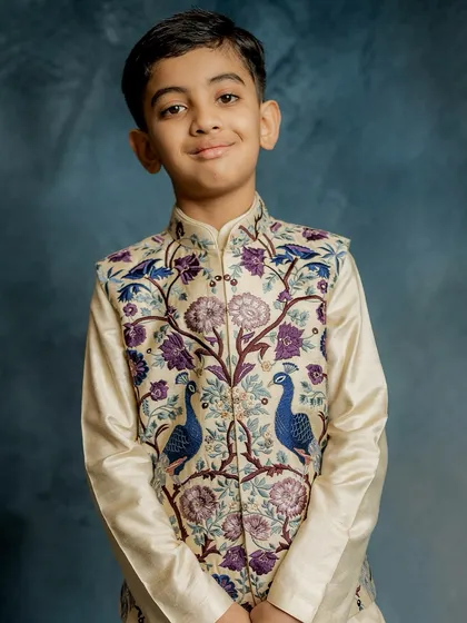 A portrait of pure elegance. This young model wears our peacock-embroidered Bundi jacket, a piece that combines traditional motifs with exquisite craftsmanship for a truly regal look.