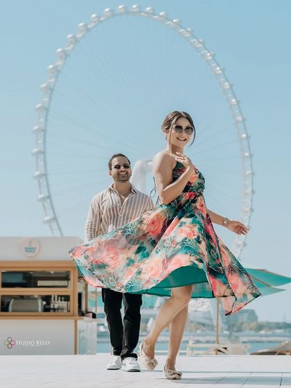 A fun, twirling shot on the Dubai beachfront with the Ain Dubai Ferris wheel in the background. This photo captures a moment of pure joy and playfulness during their destination shoot.