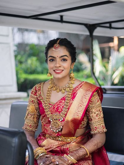 A bride seated in a golf cart, on her way to the ceremony. Even in this candid moment, her elegance and the beauty of her red saree are undeniable.