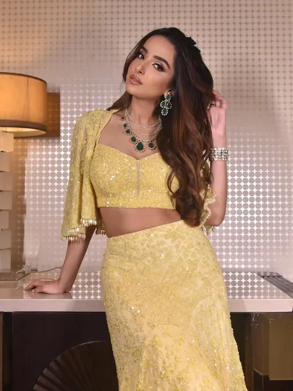 A classy cocktail look with dewy glam. I styled her hair with soft waves and a side part to complement her yellow lehenga and emerald jewelry.