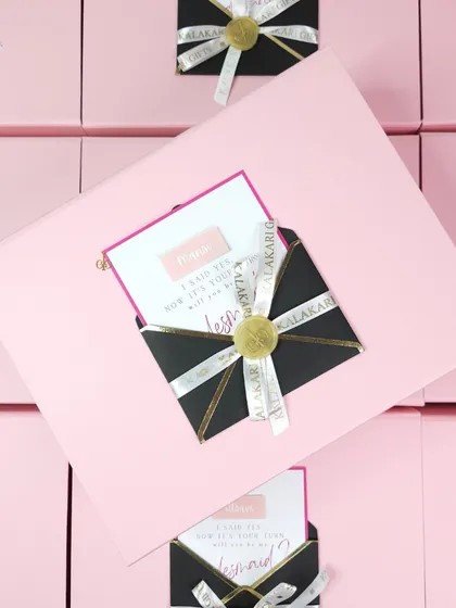 The final touch on my bridesmaid proposal boxes. Each pink box is sealed with a custom black envelope containing the "Will you be my bridesmaid?" card, tied with a branded ribbon and wax seal.