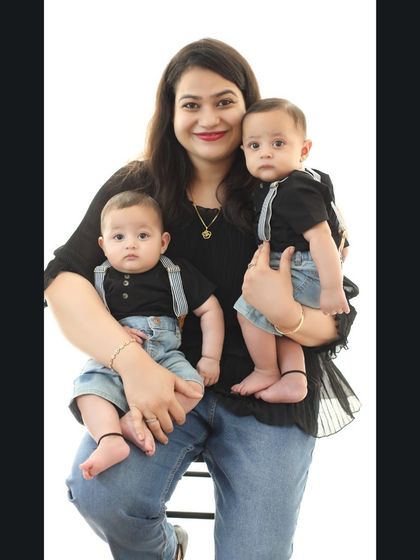 Double the joy. This proud mother holds her adorable six-month-old twin boys, who are dressed in matching outfits for their family photoshoot.