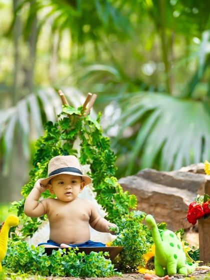 A fun, jungle-themed shoot set up in a park. The natural foliage blends perfectly with the dinosaur props and leafy teepee.