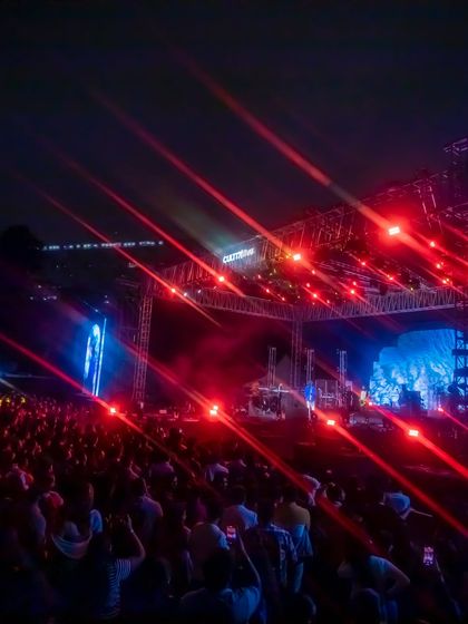 The stage is illuminated with dramatic red and blue lighting trusses, creating a powerful visual spectacle. I manage the complete technical setup, from lighting design to structural rigging, for large-scale concerts.