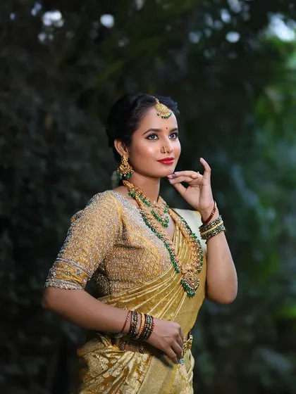 The classic combination of gold and green. This bridal set features a stunning long haram with green stone embellishments, a matching choker, and jhumkas, ideal for a traditional muhurtham ceremony.