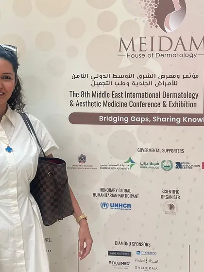 Posing by the official banner for the 8th Middle East International Dermatology & Aesthetic Medicine Conference (MEIDAM). The theme 'Bridging Gaps, Sharing Knowledge' perfectly captures the spirit of the event.