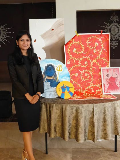 Posing with a display of my artwork. Each piece, whether on canvas or fabric, tells a different story and represents a different phase of my artistic exploration.