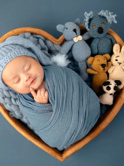 This little one is nestled amongst his tiny animal friends, creating a sweet and imaginative scene. The heart-shaped bowl adds a touch of love to this newborn portrait.