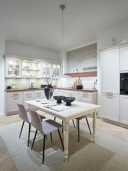 This classic white kitchen features elegant framed doors and integrated appliances, offering a timeless design that can be adapted to both modern and traditional homes.