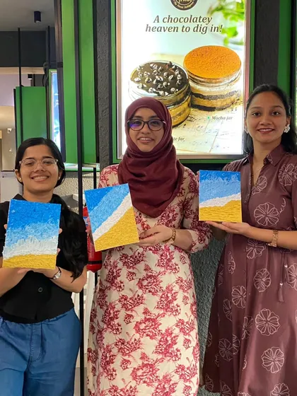 Three participants showing off their finished texture paintings of a beach scene. It's amazing how the same theme can result in three unique and beautiful interpretations.