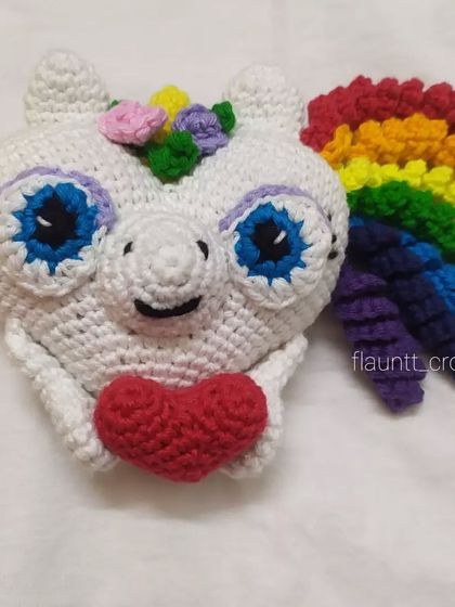A close-up of the unicorn heart plushie, showing the colorful flowers on its head and its big, sweet eyes.