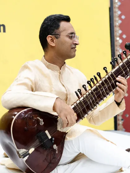 Playing a composition at the SPIC MACAY event, with a microphone setup suitable for school auditoriums.