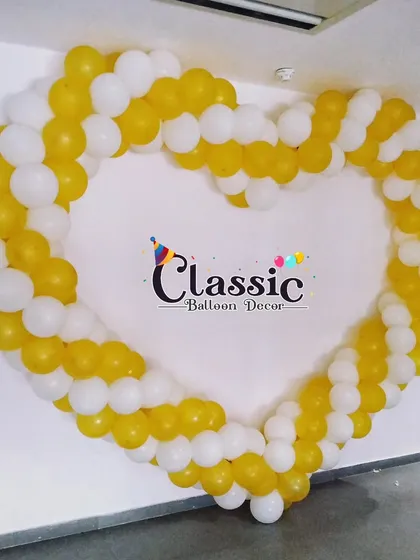 We can create balloon sculptures in different shapes, like this large heart-shaped frame made of yellow and white balloons. It's a sweet and simple backdrop for any celebration of love.