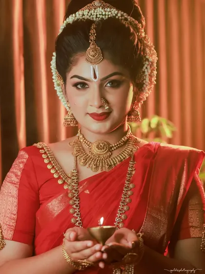 A classic portrait of a bride holding a diya (oil lamp). The warm light from the lamp illuminates her face, creating a serene and devotional mood perfect for festive or wedding ceremonies.