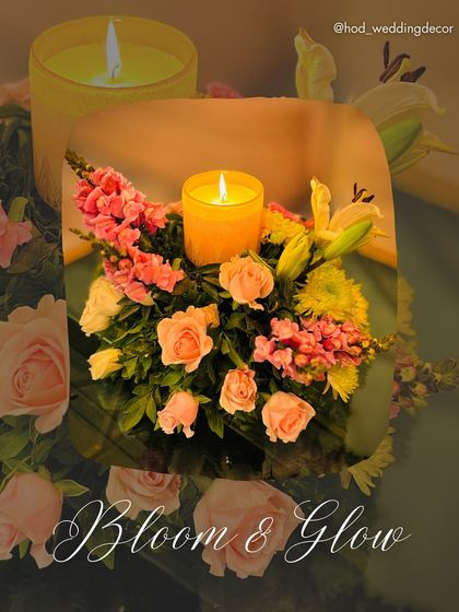 A beautiful "Bloom & Glow" detail, featuring a candle surrounded by a delicate arrangement of pastel roses and lilies, perfect for a romantic table setting.