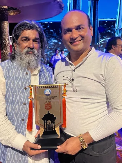 A photo with Shri Nitin Desai after being honoured at his event. I am holding the memento he presented to me.