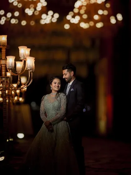 A grand and romantic portrait of the couple at their engagement party, surrounded by the warm glow of candelabras and chandeliers.