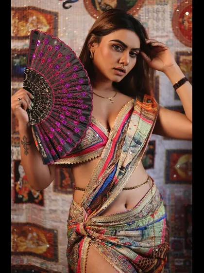 A stylish portrait of a model in a modern saree, holding a fan as a prop to add a touch of drama and personality.