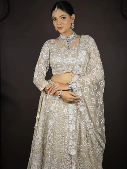A full front view of the ivory lehenga with geometric embroidery, paired with a diamond and emerald jewellery set.