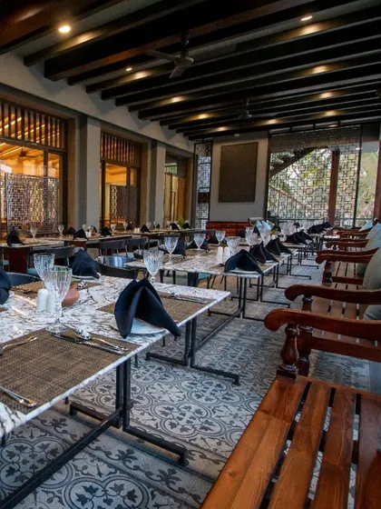 Another perspective of the restaurant's outdoor section, highlighting the traditional wooden benches and intricate window details. The design blends classic Indian architectural elements with modern restaurant functionality.