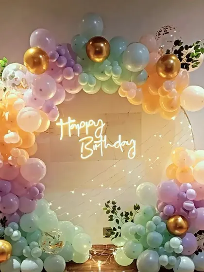 A dreamy pastel rainbow balloon ring for a birthday. This soft and elegant color scheme is accented with gold balloons and fairy lights, creating a magical photo backdrop.