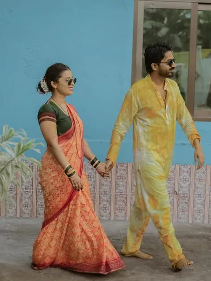 A cool, candid shot of the couple walking hand-in-hand after their Haldi ceremony. The contrast with the blue wall makes for a great photo.