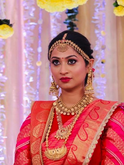 Candid moments often make the most beautiful images. This bride looks picture-perfect in her red and gold attire, a classic combination for a South Indian wedding ceremony.