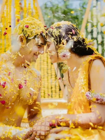 A couple, covered in yellow petals and turmeric, share an intimate moment during their 'phoolon wali haldi'.