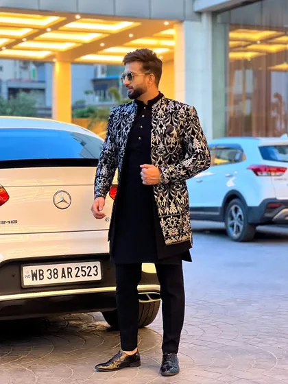 This black and silver Indo-Western sherwani is a perfect example of our fusion wear. The detailed embroidery on the jacket, paired with a classic black kurta, offers a sophisticated look for a reception or sangeet.