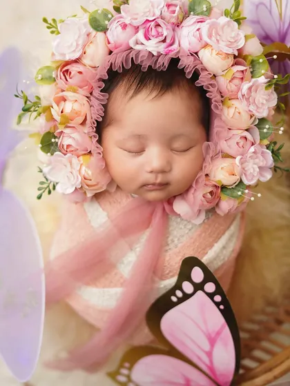 A close-up of the 'baby butterfly', focusing on the intricate details of the flower bonnet and her peaceful, sleeping face.