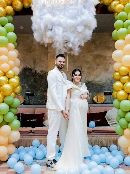 The happy couple surrounded by a sea of blue balloons. This photo captures the beautiful aftermath of their cloud-themed gender reveal, a moment of pure happiness and celebration.