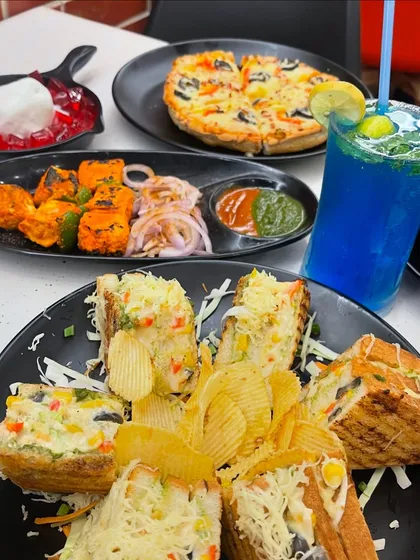 Good food equals a good mood, and this spread of sandwiches, pizza, paneer tikka, and a refreshing mojito is sure to make you happy.