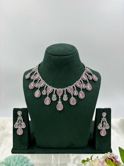 A contemporary silver-plated necklace set with teardrop-shaped stones. This design is available in emerald green, pink, red, and dark blue, offering a sleek and modern look for any occasion.